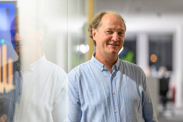 Close-up portrait of cheerful mature businessman looking at camera while standing in a modern office building