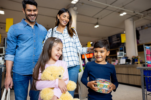 Happy Latin American family leaving the supermarket after shopping for groceries