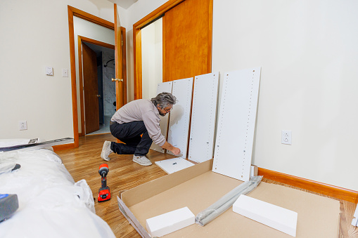 Furniture assembly. Mature man is assembling the furniture in the new house.