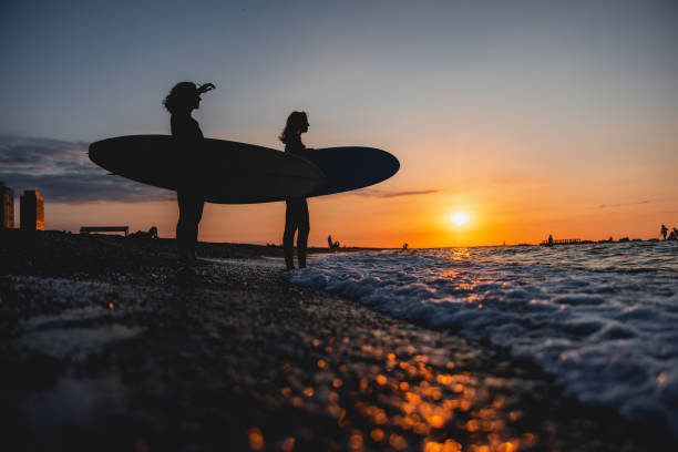 istock Two Female Surfers In Wetsuits Walking Into The Ocean With Their Surfboards During A Beautiful Sunset In Barcelona 1976229950