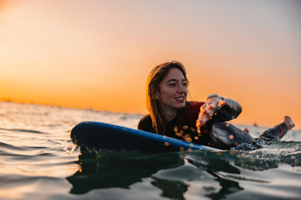 Attractive Surfer Girl Paddling On A Surfboard During A Sunset