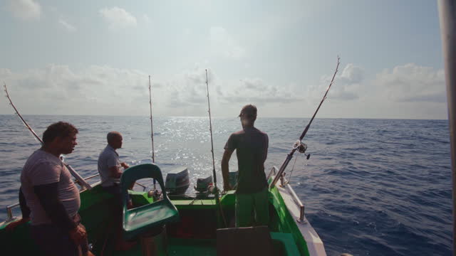 Three fishermen are adjusting the rods and waiting for a bite during the deep sea fishing trip in Sri Lanka.