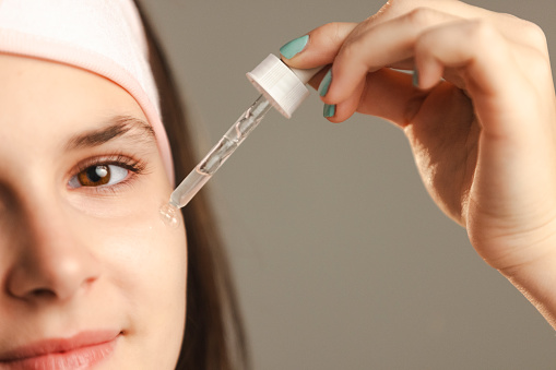 Young girl applying a drop of serum to her face