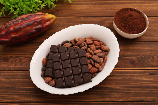 Chocolate with cocoa beans and cocoa powder on a wooden background