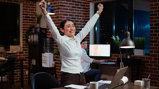 Happy worker jumping from office chair, feeling excited after learning of upcoming promotion, rewarded for good results. Cheerful employee exulting from joy, celebrating, camera A