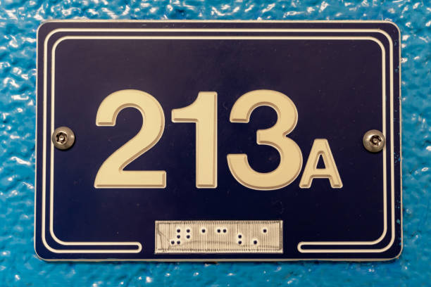 istock Blue 213A sign with white lettering and braille, on a blue block wall. 1976323683