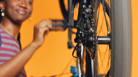 Close up shot of bike wheel being tested by repairman doing servicing. Focus on bicycle tires being fixed by professional in blurry background checking for faults in break rotor