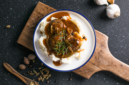 delicious meatballs on hot potato puree with cheese sauce on background view from above close-up