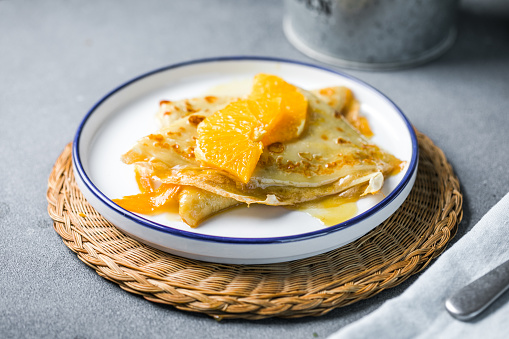 Delicious crepes suzette with orange syrup on plate