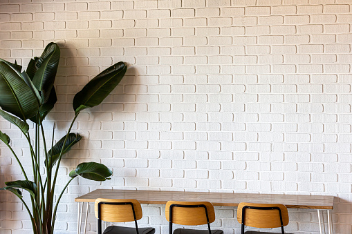 Cafe with white brick wall, featuring empty tables and chairs for a clean and welcoming design.