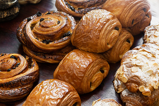 Close-up view of chocolate pastries, almond croissants, and delightful spiral raisin Danish.