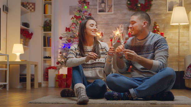 istock Cheerful couple on christmas day holding hand fireworks 1976491588