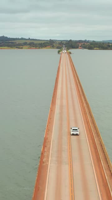 Car crossing a suspension bridge over the vast ocean