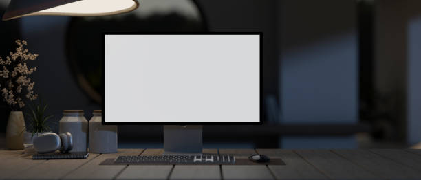 istock A white-screen computer mockup on a wooden plank table in a modern dark room at night. 1976545412