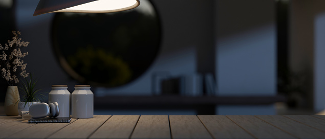 A space for displaying your product, a headphone, a book, and decor on a wooden plank table in a modern dark room at night, illuminated by dim light from a lamp. 3d render, 3d illustration