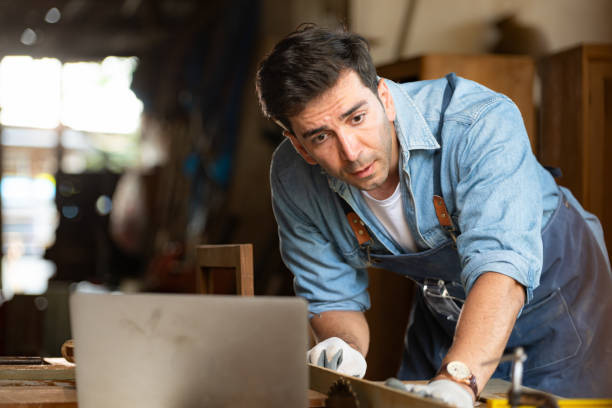 istock Carpenter working on laptop in his workshop at a woodworking factory 1976553299
