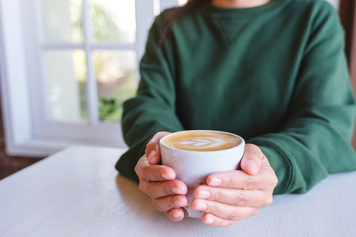 Closeup image of a woman holding a cup of latte coffee