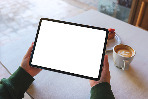 Top view mockup image of a woman holding digital tablet with blank white desktop screen in cafe