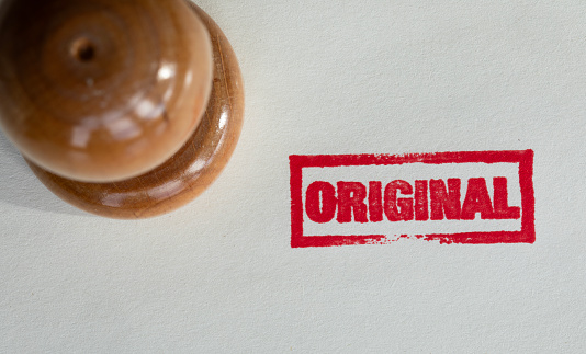 Wooden original stamp on white textured paper. Horizontal composition with copy space. Directly above view.