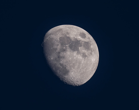 The full Moon is seen isolated on a white background. High contrast, high resolution image taken with a full frame dslr camera.