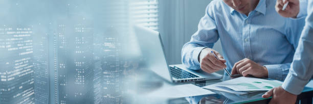 Business people meeting with financial charts analysing data analytics reports. Finance, consulting, auditing, teamwork, collaboration, strategy. Sales and marketing data. City background.