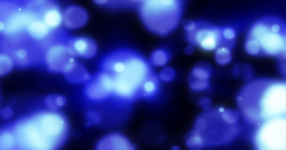 Abstract blue blurred holiday background with magical bokeh of glowing bright light energy small particles of flying dots on a black background.