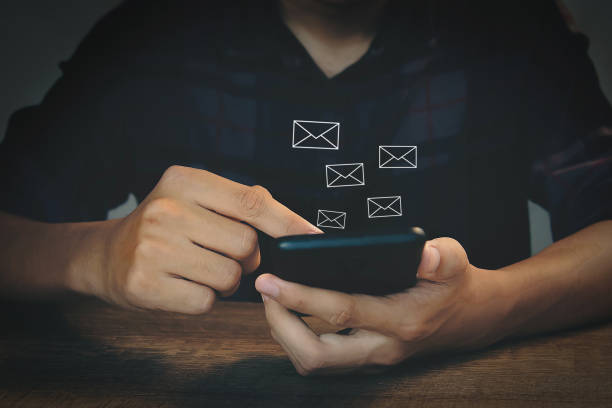 istock New email notification. Communication. Businessman holds smartphone with email notification in icon. 1976744908