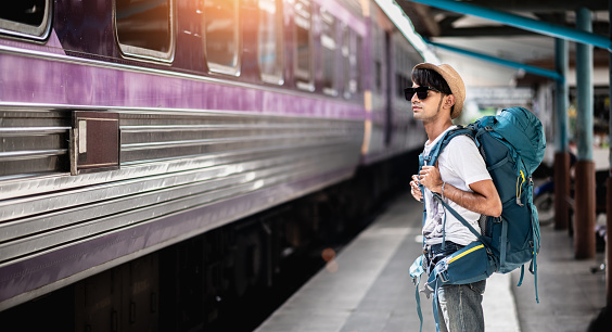 Traveler waits train at train station for travel in summer. Travel concept.