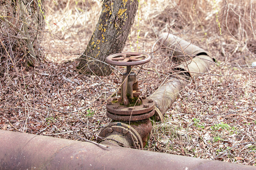 Large metal valve on a pipe in nature.