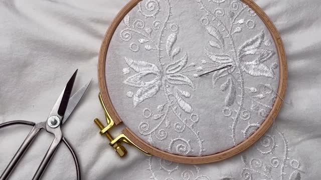 The process of embroidering a shirt with white threads on white fabric.