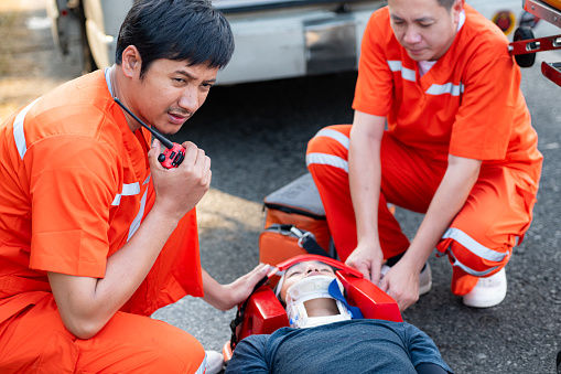 The paramedic  is assisting an injured man in an emergency situation on the road.