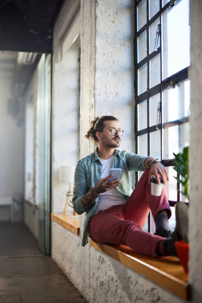 istock Male freelancer using cell phone on coffee break by the window. 1976854051