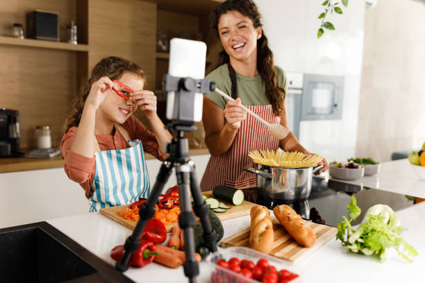istock Happy mother and daughter having a live broadcast while preparing lunch in the kitchen. 1976864607