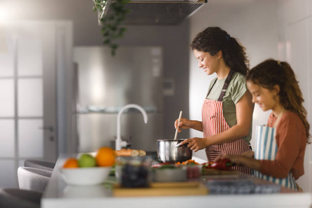 istock Happy mother and daughter making lunch in the kitchen. 1976865133