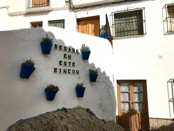 Ancient house of Andalusia with the signboard besame en este rincon translation kiss me in this corner