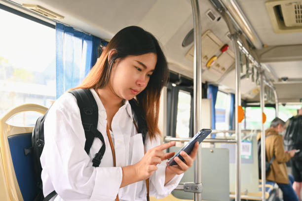 istock Beautiful young woman using smartphone while while riding a bus in the city 1976888733