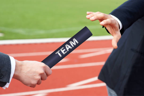 istock Passing team baton in relay race business men hand over 1976888916