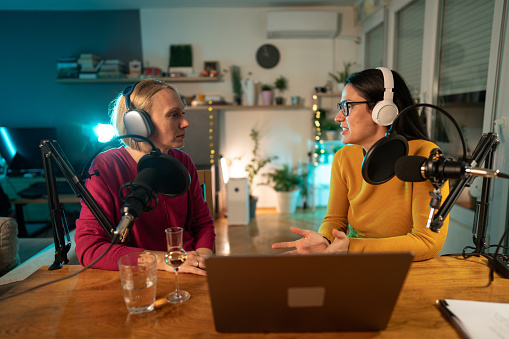 Woman recording a radio podcast with female guest in studio