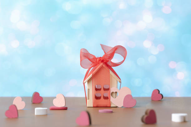 istock House model with red bow and decorative valentines hearts over holiday defocused lights. Valentineâs day concept 1976908903