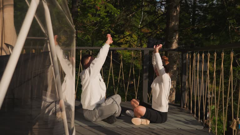 Teacher demonstrates hand-raising asana to woman