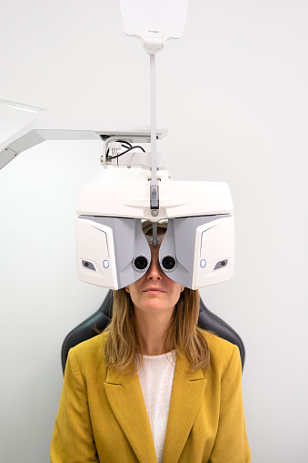 Vertical portrait of a woman during an eye test exam sitting on a clinic
