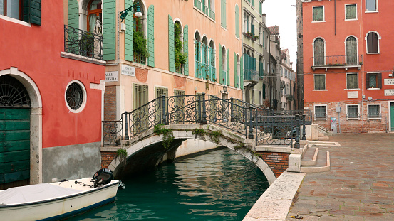 Venice picturesque small bridge 'Ponte Giustinian' and buildings with attractive complementary red and green colors.