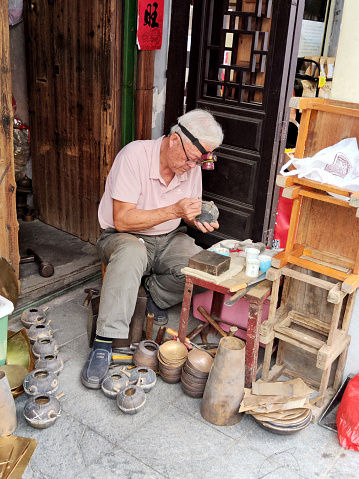 Local artisan working on a street in Chaozhou City centre. Chaozhou is a cultural center of the Chaoshan region in Guangdong province.