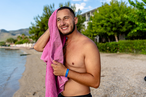 After his invigorating swim, the young man dries off, feeling the warmth of the towel complement the lingering touch of the sea