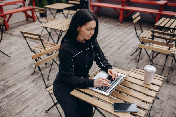 istock beautiful young woman using technology outdoors and drink coffee. 1977086799