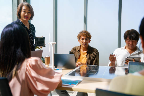 istock Engaged team members are discussing over solar panel models in a bright office, with a focus on alternative energy solutions. 1977121010