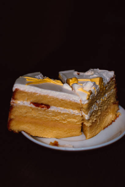 istock Pieces of fresh lemon sponge cake with cream on black background 1977124749