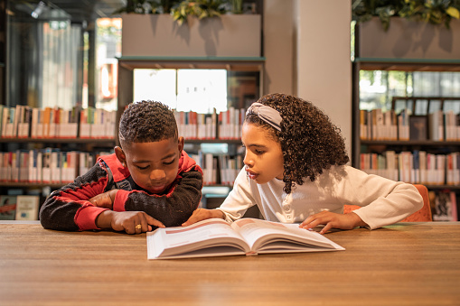 A group of young black and diverse school children in a dutch library