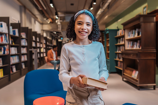 Portrait of a diverse young female school child reader in a library in the netherlands