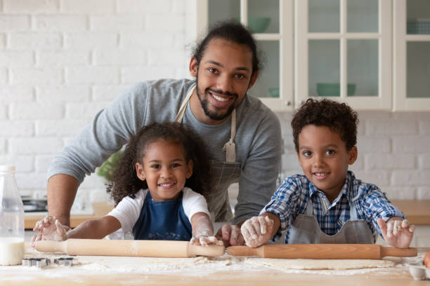 istock Happy Black dad helping children in aprons to bake pie 1977155490